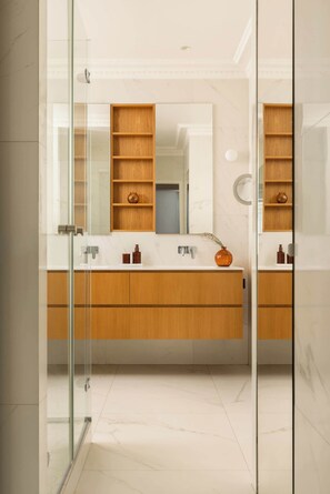 Un bagno moderno con cabina doccia in vetro, mobile lavabo in legno e un ampio specchio.