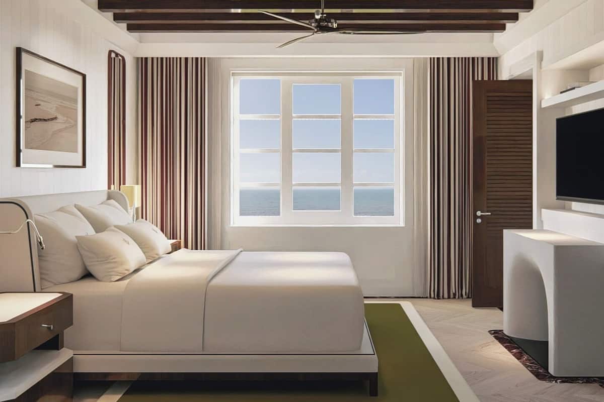 A modern bedroom with a bed, a TV, a window with a view, and a ceiling fan.