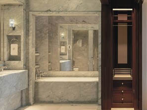 A modern bathroom with a marble wall, a large mirror, a bathtub, and a wooden door. - Cipriani Punta Del Este  (Punta del Este)