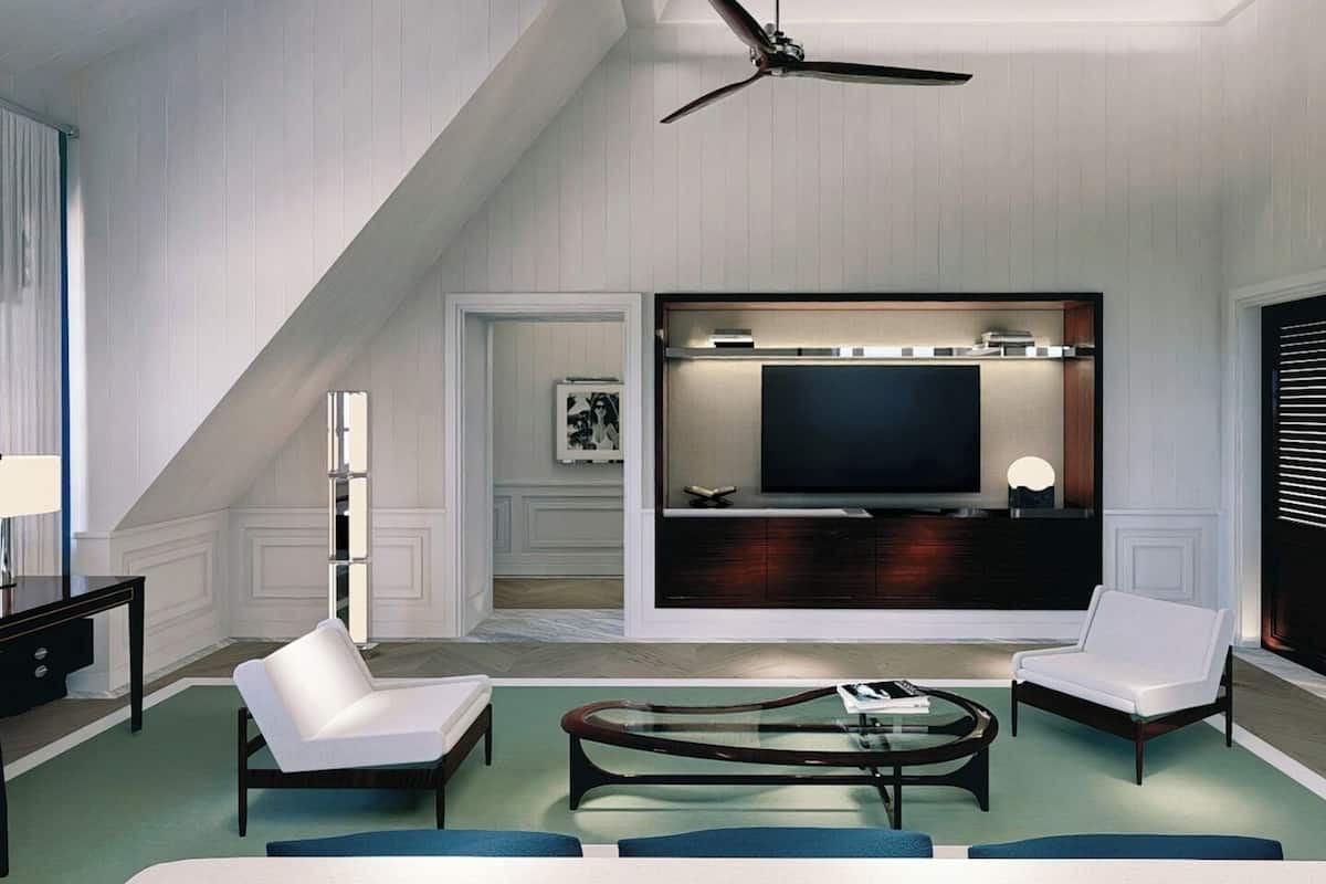 A modern living room with a television, two white armchairs, a coffee table, and a ceiling fan.