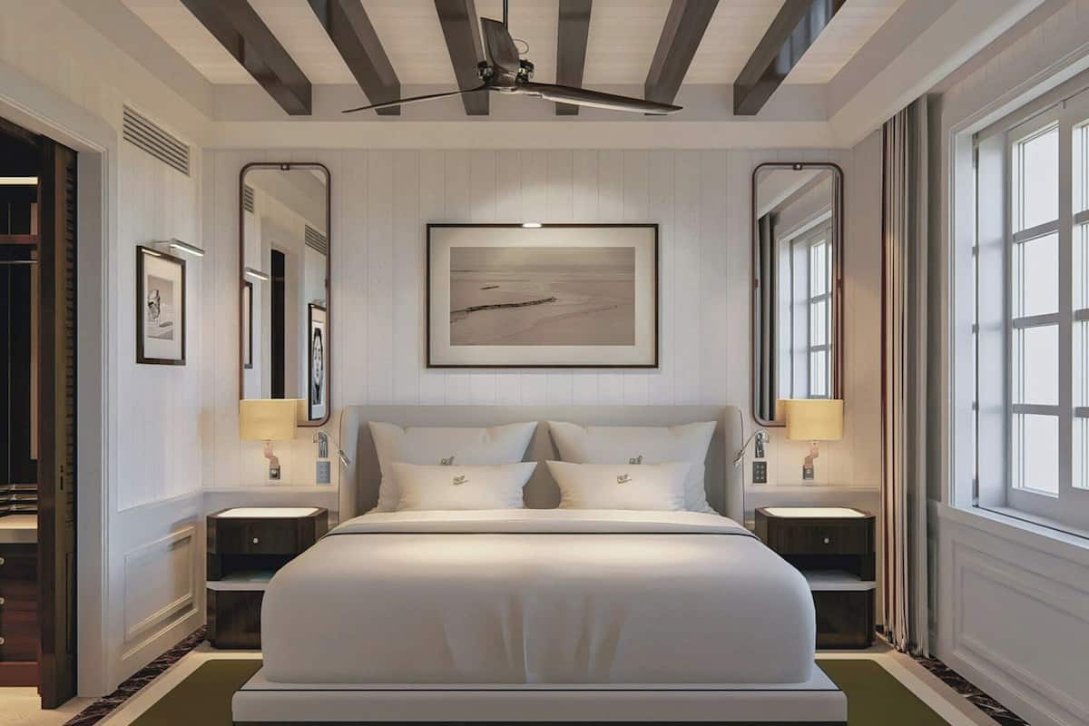A large bed with a headboard, two bedside tables with lamps, a large framed picture above the bed, and a window on the right side.