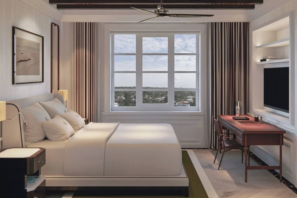 A modern hotel room with a large bed, a desk, a TV, and a window with a city view.