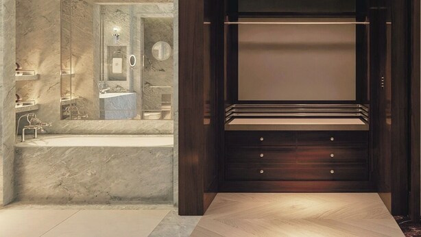 A modern bathroom with a marble wall, a built-in sink, and a dark wooden vanity with drawers. - Cipriani Punta Del Este  (Punta del Este)