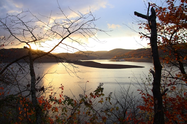 A lake surrounded by trees with a sunset in the background.
