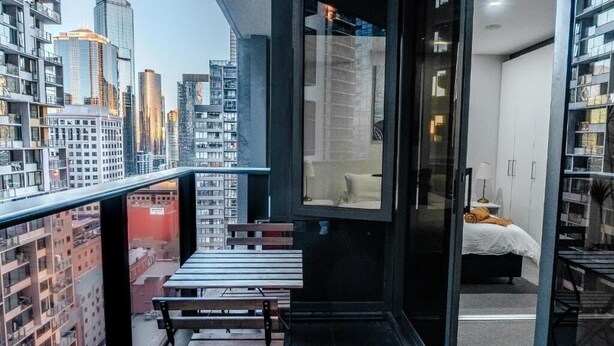 Een modern appartement met balkon, een bed en uitzicht op de stad.