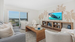 Uma sala de estar com sofá, mesa de centro, televisão e objetos decorativos.