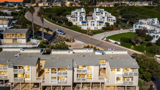 Zona residencial com edifícios modernos de vários andares, uma estrada curva e céu claro.