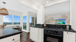 Cozinha moderna com uma ilha grande, forno embutido e vista para o oceano.