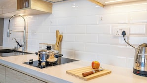 A modern kitchen with white tiles, stainless steel appliances, and wooden cabinetry. - Cozy studio apartment in lovely Nairobi with amazing city views (Nairobi)