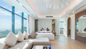 Ett modernt hotellrum med en stor säng, en soffa, ett soffbord i trä och utsikt över staden.