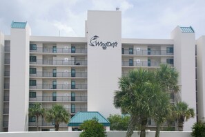 Ein mehrstöckiges Hotel mit Balkonen, dem gut sichtbaren WindDrift-Logo und Palmen im Vordergrund.