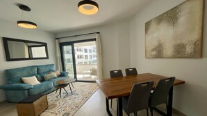 Ein modernes Wohnzimmer mit einem blauen Sofa, einem Holzesstisch und einem großen abstrakten Gemälde.