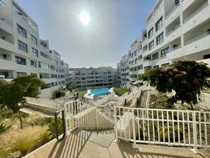 A modern apartment complex with a central swimming pool, white balconies, and a clear sky. - Estepona Center, Pool and Beach (Estepona)