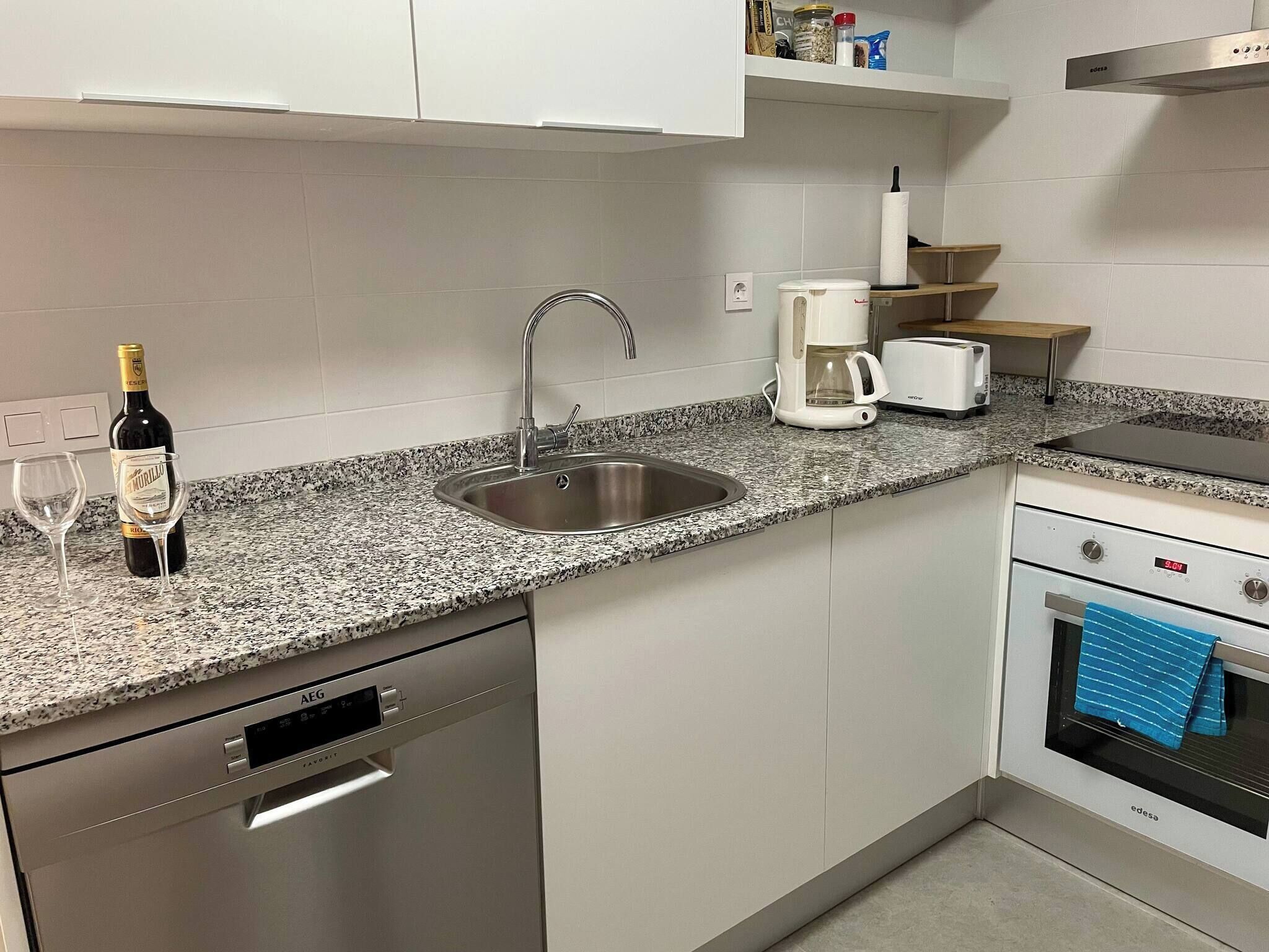 A kitchen with a stainless steel sink, a coffee maker, a toaster, and a dishwasher.