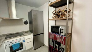 Eine kompakte Küche mit Edelstahlkühlschrank, Mikrowelle und eingebautem Backofen.