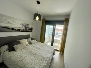 Une chambre à coucher avec un lit, une table de chevet, une œuvre d’art accrochée au mur et une vue par la fenêtre.