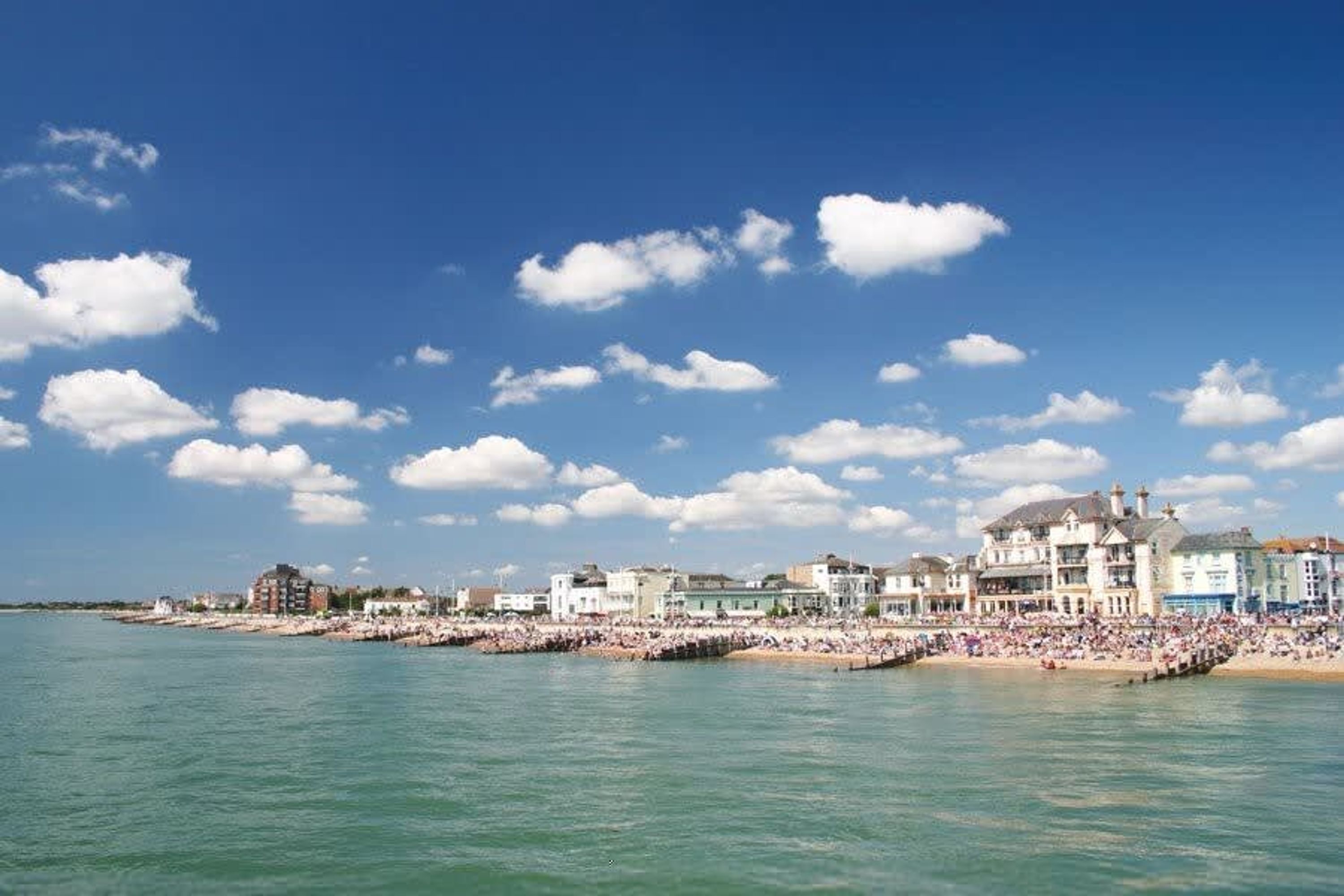 A coastal town with a beach, buildings, and a clear sky.