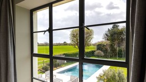 A window with a view of a swimming pool and a green landscape. - Chic Harbour Retreat for 10 With Pool (Chichester)