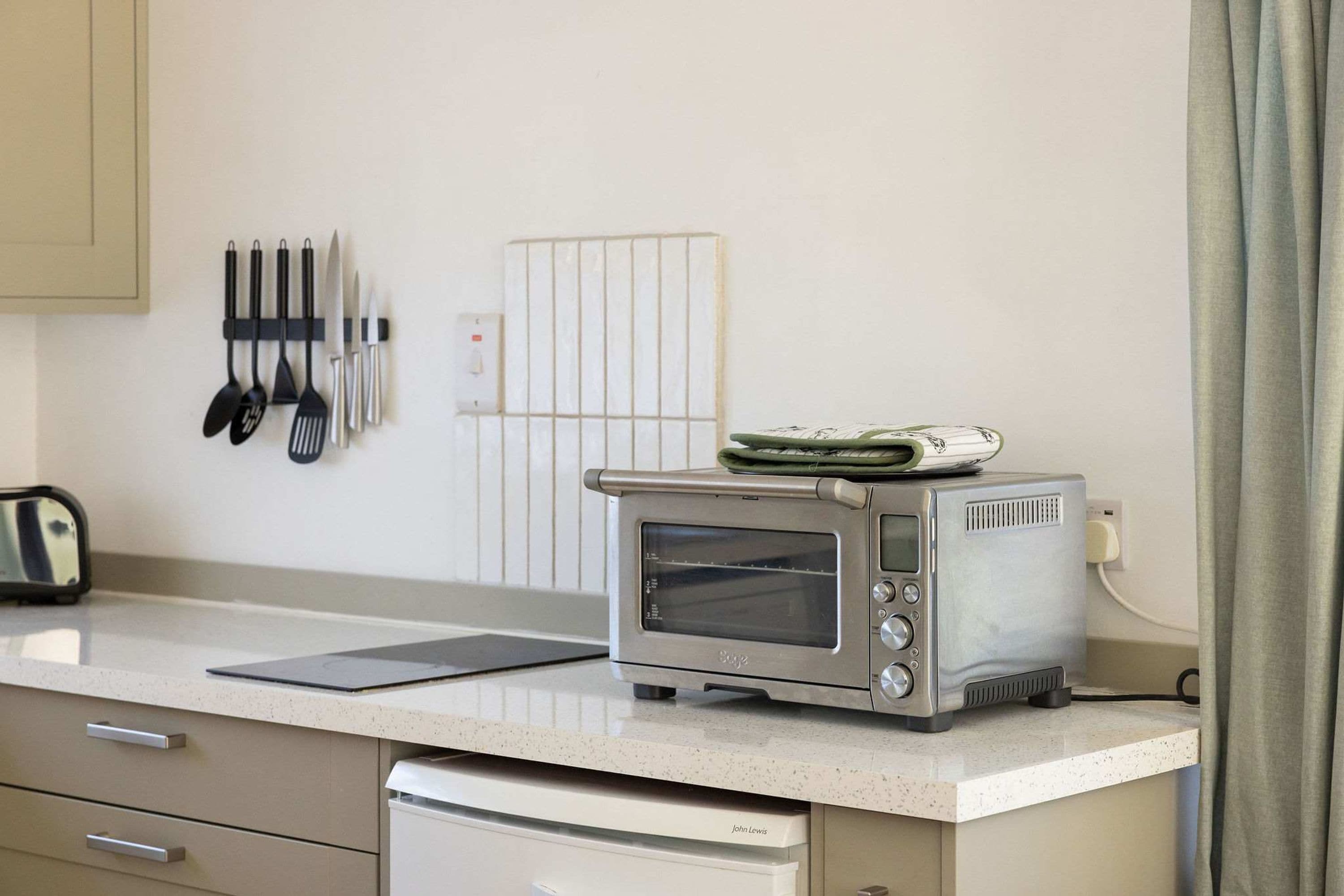 Een kitchenette met een toaster, waterkoker en een houder voor de waterkoker aan de muur.