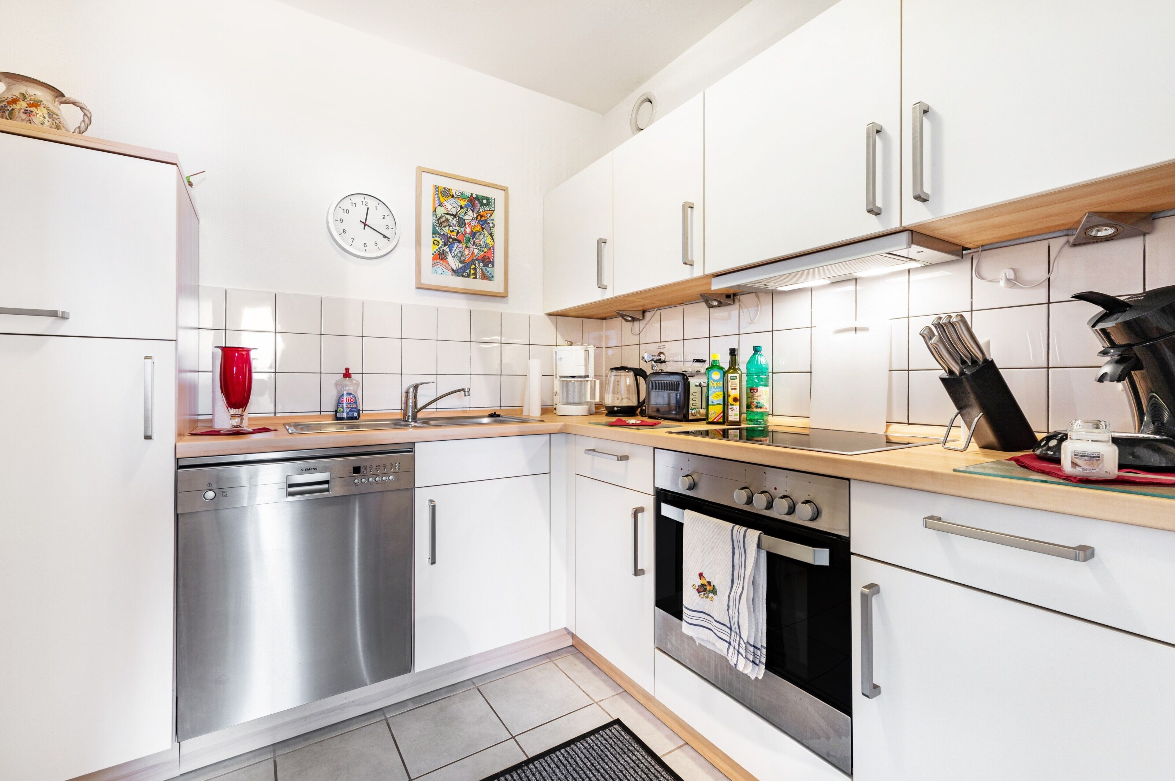A modern kitchen with white cabinets, stainless steel appliances, and a tiled backsplash.