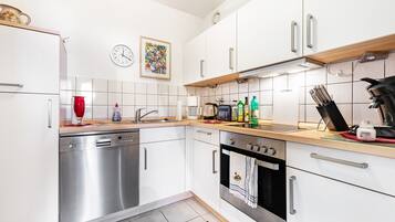 A modern kitchen with white cabinets, stainless steel appliances, and a tiled backsplash.