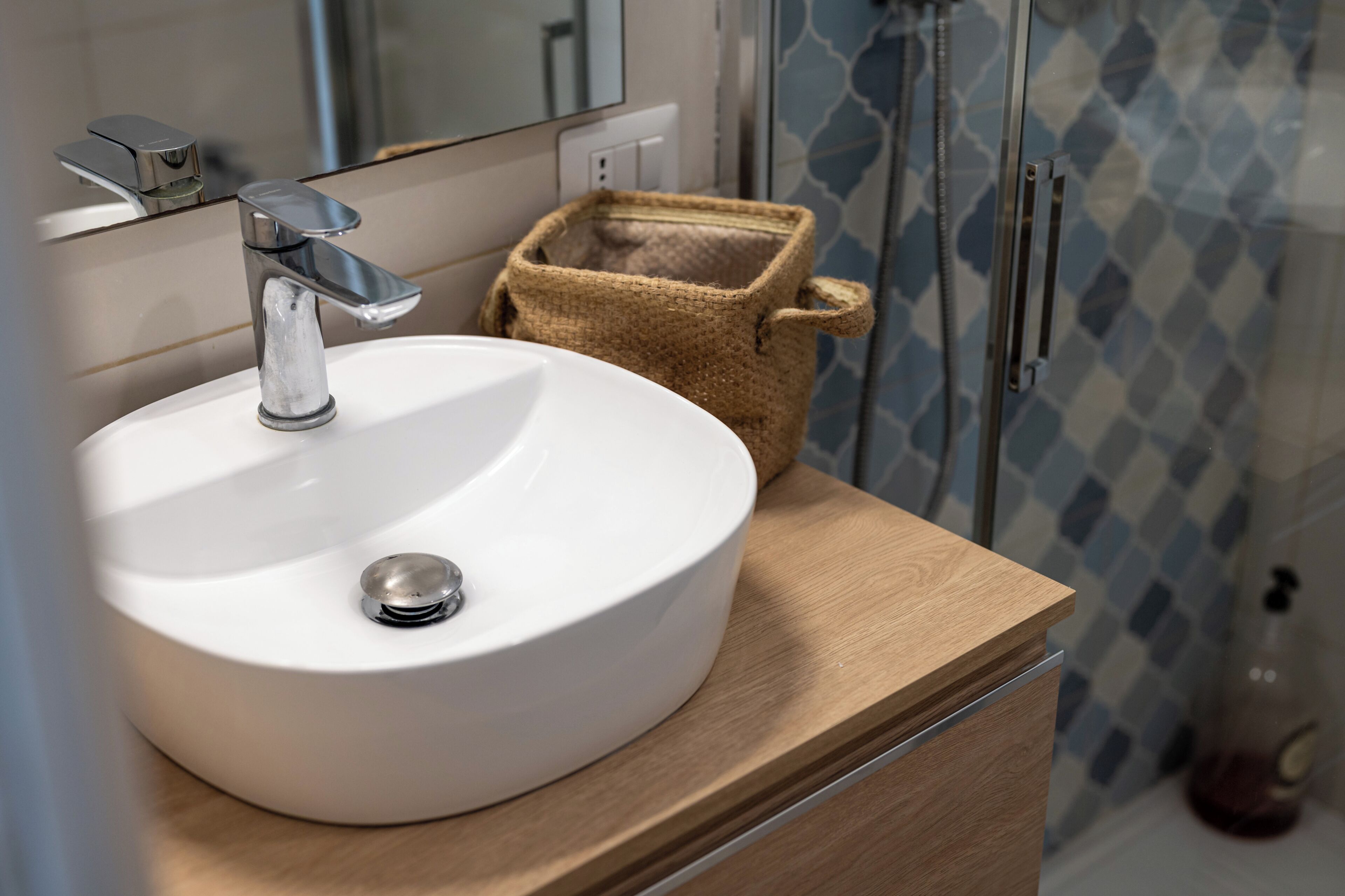 A bathroom with a white sink, chrome faucet, and a wooden vanity.