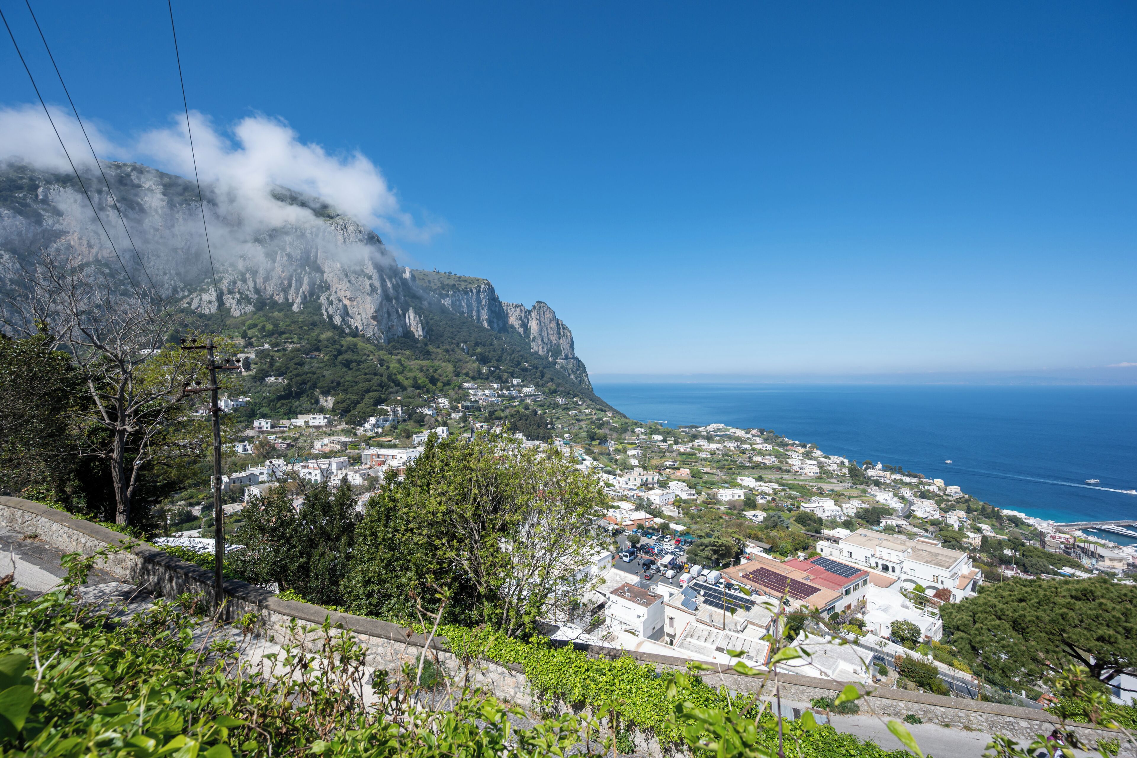 A coastal town with buildings, a mountain, and the sea.