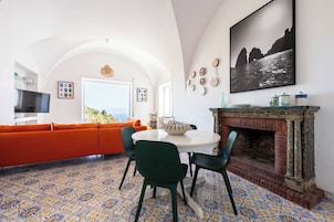 Una sala de estar moderna con un sofá, una mesa redonda, sillas, una chimenea y un ventanal grande.