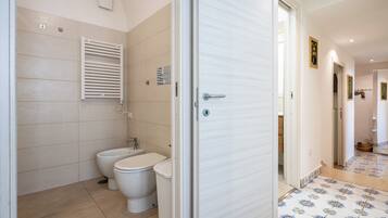 Un bagno con il water, bidet e porta asciugamani.