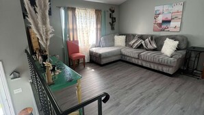 Una sala de estar moderna con un sofá gris, una mesa de comedor y una escalera.