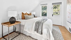 A bedroom with a bed, bedside tables, a window, and a door. - Spacious Linden Hills 4BD 2A Family Home (Minneapolis)