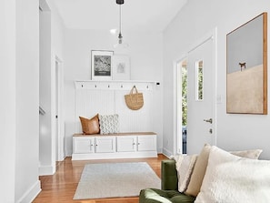 A modern entryway with a bench, a hanging light fixture, a coat rack, and a framed picture on the wall. - Spacious Linden Hills 4BD 2A Family Home (Minneapolis)