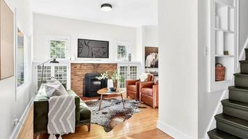 A spacious living room with a fireplace, a staircase, and a view of the outdoors.