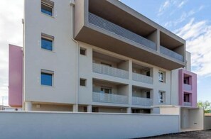 A multi-story residential building with balconies, a flat roof, and a simple facade. - Balcony Tower View - Modern Apartment with Private Parking (Pisa)