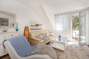 A modern living room with a sofa, coffee table, and a view of the outdoors. - Cozy vacation apartment in Trassenheide, only 150 m from the beach (Trassenheide)