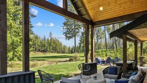 A covered outdoor seating area with a view of a golf course. - Memories Made on Prospector's 16th Fairway-Spa & Pets (Cle Elum)