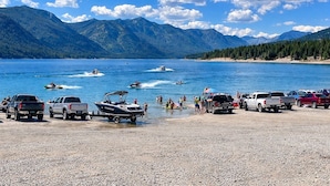 A lake with boats, a beach with parked vehicles, and mountains in the background. - Memories Made on Prospector's 16th Fairway-Spa & Pets (Cle Elum)