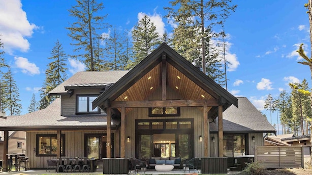 A modern house with a large porch, a dining area, and a covered outdoor seating area. - Memories Made on Prospector's 16th Fairway-Spa & Pets (Cle Elum)