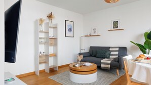 A modern living room with a sofa, coffee table, and shelves. - Cozy 2BR Eiffel Tower Area (Paris)