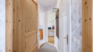 A hallway with wooden doors, a white wall with a marble-like texture, and a ceiling light fixture. - Your perfect time-out in Duhnen - cozy, central and close to the beach (Cuxhaven)