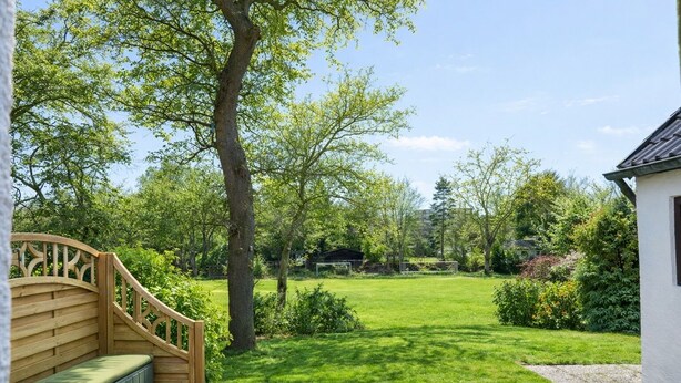 A garden with a wooden bench, a lawn, and a building in the background. - Your perfect time-out in Duhnen - cozy, central and close to the beach (Cuxhaven)