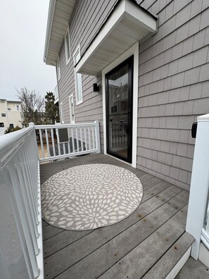 A residential porch with a patterned rug, a white railing, and a sliding glass door. - Beautifully Renovated 4br Home on Avalon - Stone Harbor Border - Pet Friendly (Avalon)