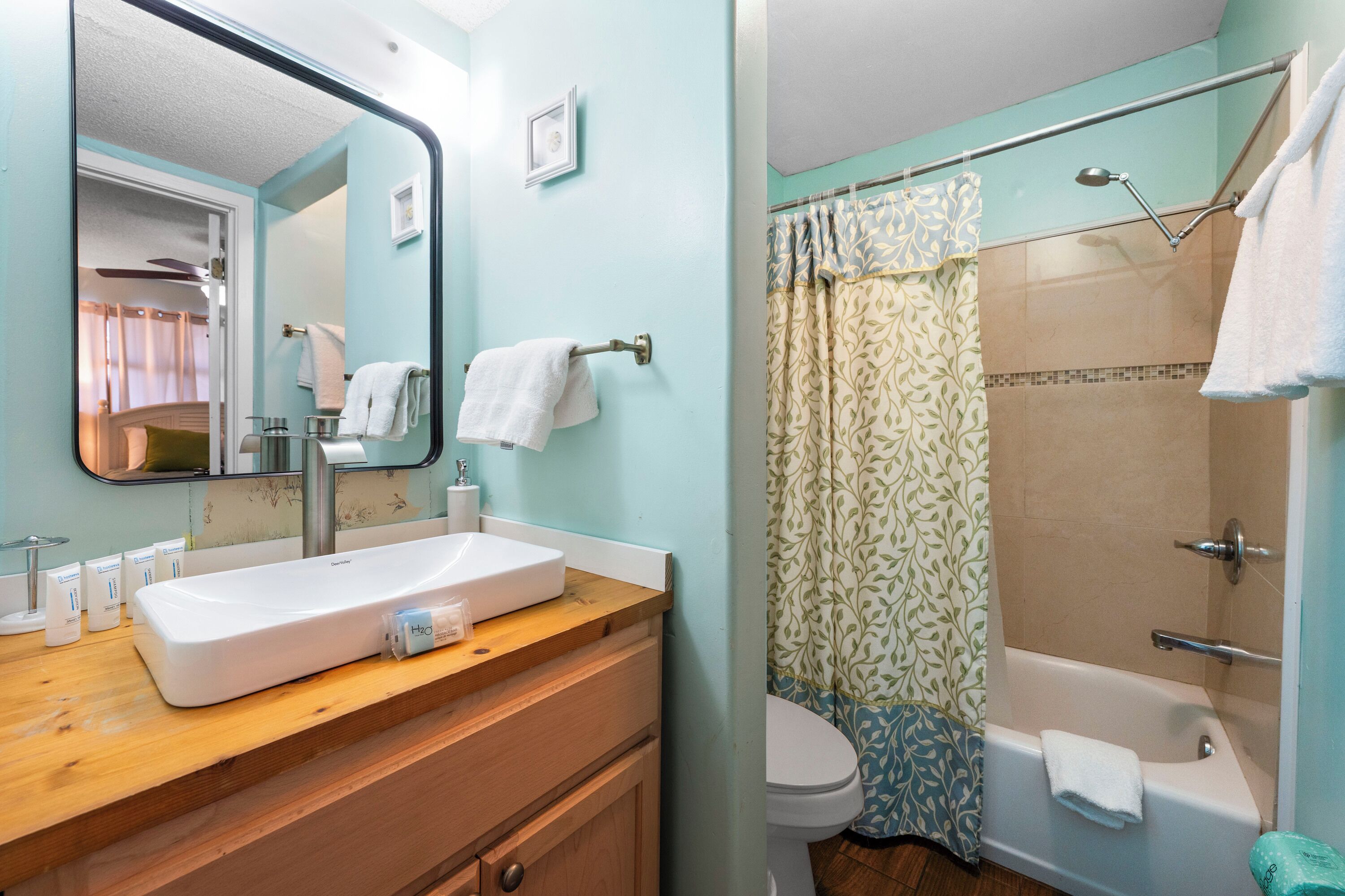 A bathroom with a sink, mirror, and shower area.
