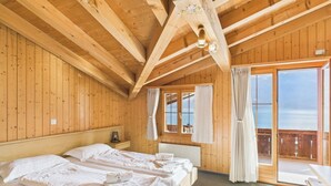 A wooden cabin with two beds, a balcony with curtains, and a view of the sea. - Hotel Wildbach Brienz (Brienz)
