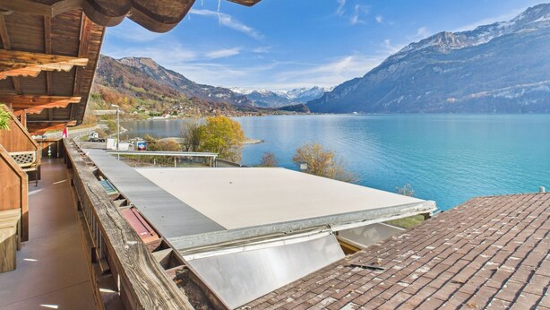 A wooden balcony with a view of a lake and mountains. - Hotel Wildbach Brienz (Brienz)