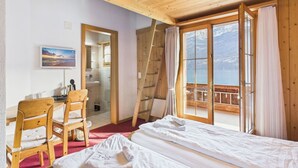 A wooden cabin room with a bed, chairs, a desk, a bathroom, and a balcony with a view. - Hotel Wildbach Brienz (Brienz)