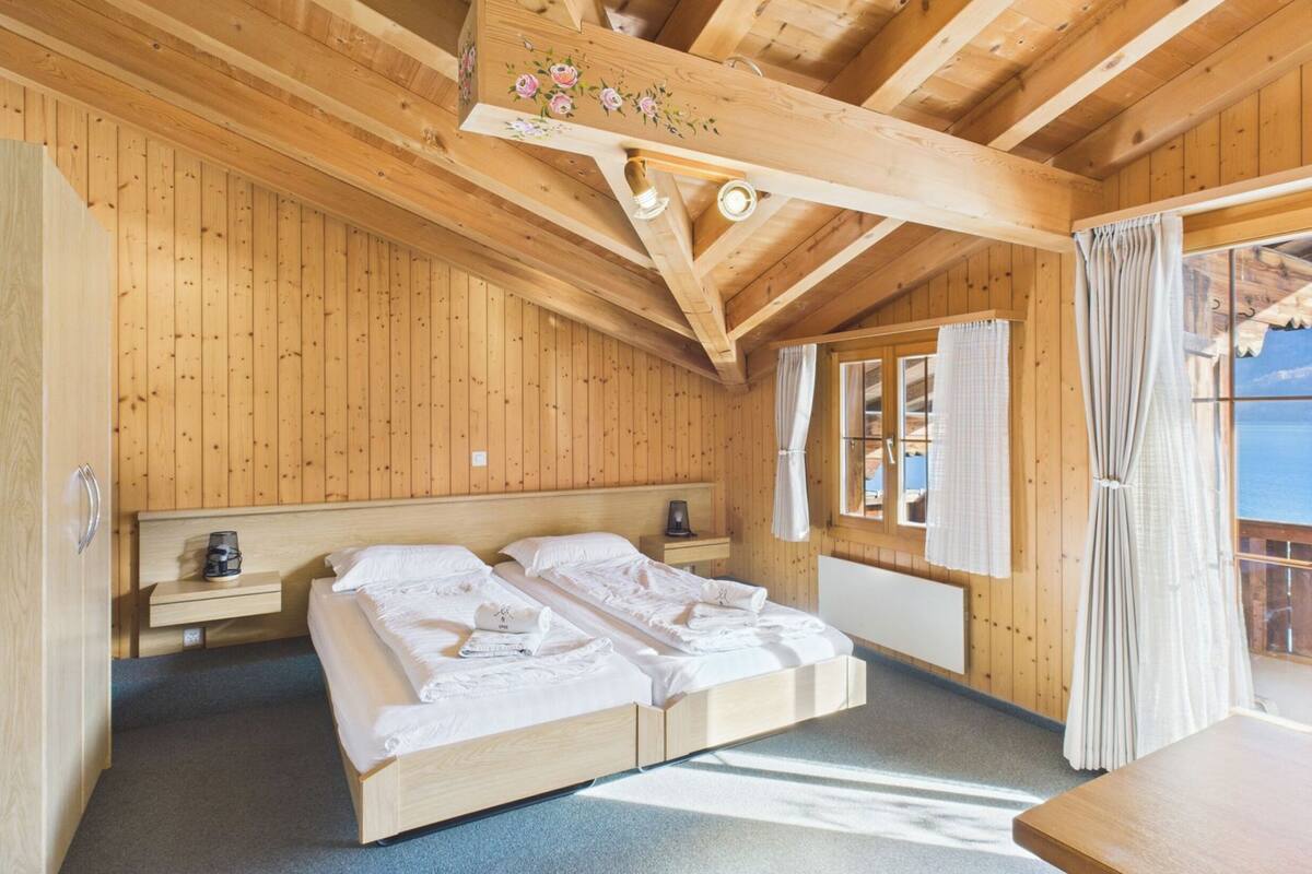 A wooden cabin bedroom with a bed, bedside tables, and a window with curtains.
