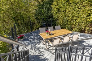 Une terrasse extérieure avec une table et des chaises en bois, entourée de verdure.