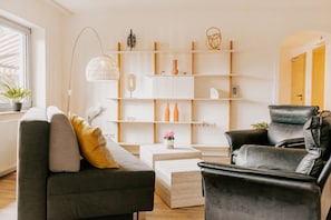 Un salon moderne comprenant un canapé, un fauteuil en cuir, une table basse et une bibliothèque.