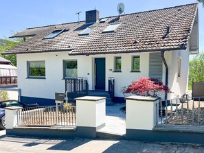 Une maison de plain-pied avec un toit en tuiles, une porte d’entrée et un petit porche.